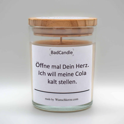 Soja Duftkerze im Glas mit Deckel aus Kiefernholz mit einem Label. Aufschrift: BadCandle - Öffne mal dein Herz. Ich will meine Cola kalt stellen.